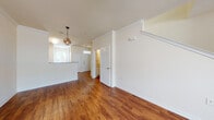This two-floor residence offers a well-organized layout with a thoughtful mix of finishes throughout. The main living area is spacious and open, showcasing rich hardwood-style flooring, crown molding, and a ceiling fan with integrated lighting. Natural light flows in through windows, enhancing the bright, neutral color palette of cream-toned walls. A decorative orb pendant light fixture adds a stylish focal point to the open-concept area connecting the living space to the kitchen and entryway.

The kitchen features rich, warm-toned cabinetry, light countertops, a double basin sink, and white appliances including an electric range and over-the-range microwave. A breakfast bar counter opens toward the main living area, making it ideal for casual dining and entertaining.

The bedrooms are carpeted for comfort, with one featuring a large window with outdoor views and a spacious walk-in closet with built-in shelving. Additional bedrooms provide ample space and multiple outlets.

The full bathroom includes tile flooring, a tub-shower combination with tiled surround, a vanity with granite-style countertops, and a window for natural ventilation. A separate half bath with hardwood-style flooring is also present. The staircase connects both floors, completing this well-appointed multi-level layout.