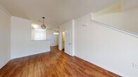 This two-floor residence offers a well-organized layout with a thoughtful mix of finishes throughout. The main living area is spacious and open, showcasing rich hardwood-style flooring, crown molding, and a ceiling fan with integrated lighting. Natural light flows in through windows, enhancing the bright, neutral color palette of cream-toned walls. A decorative orb pendant light fixture adds a stylish focal point to the open-concept area connecting the living space to the kitchen and entryway.

The kitchen features rich, warm-toned cabinetry, light countertops, a double basin sink, and white appliances including an electric range and over-the-range microwave. A breakfast bar counter opens toward the main living area, making it ideal for casual dining and entertaining.

The bedrooms are carpeted for comfort, with one featuring a large window with outdoor views and a spacious walk-in closet with built-in shelving. Additional bedrooms provide ample space and multiple outlets.

The full bathroom includes tile flooring, a tub-shower combination with tiled surround, a vanity with granite-style countertops, and a window for natural ventilation. A separate half bath with hardwood-style flooring is also present. The staircase connects both floors, completing this well-appointed multi-level layout.