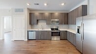 Located at 4301 Dominion Forest Cir in Glen Allen, VA, this single-floor, 2-bedroom, 2-bathroom residence offers a thoughtfully designed layout with consistent wood-style flooring and a neutral color palette throughout. The combined kitchen and living area serves as the heart of the home. The kitchen is outfitted with dark wood-tone cabinetry, light subway tile backsplash, white countertops, and a full suite of stainless steel appliances including a range, microwave, dishwasher, and a side-by-side refrigerator with an in-door water and ice dispenser. The living room features vertical blinds along a sliding glass door, allowing ample natural light to filter in. Both bedrooms are comfortably sized, featuring neutral walls and windows that bring in natural light. The primary bedroom includes a ceiling fan and is accompanied by an en-suite bathroom boasting a long vanity with dark cabinetry, a walk-in glass shower, and direct access to a dedicated walk-in closet with wire shelving. The second bathroom mirrors the modern aesthetic, featuring a matching vanity and a full tub-shower combination. Two closets provide practical storage throughout the residence.