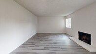 This contemporary apartment, located at 7767 La Riviera Dr in Sacramento, CA, offers a well-designed single-floor living space. The interior showcases a fresh, modern aesthetic with newly installed wood-look flooring throughout, creating a cohesive and stylish appearance. The open floor plan enhances the sense of space, with multiple rooms benefiting from large windows fitted with vertical blinds, allowing for abundant natural light.

The living area is a standout feature, boasting a cozy fireplace with a minimalist white surround, perfect for creating a warm ambiance. The updated kitchen, while compact, is efficiently designed with white cabinetry, contrasting black appliances, and a practical galley layout. It includes essential amenities such as a full-sized refrigerator and stove.

Bedrooms are generously sized, with ample wall space for furniture placement and built-in closets for storage. The bathroom features a clean, white design with a combination tub and shower, complemented by a vanity with a speckled countertop. Throughout the apartment, neutral-toned walls provide a blank canvas for personalization.

The property's layout suggests additional rooms that could serve as offices, dining areas, or extra bedrooms, offering flexibility to suit various lifestyle needs. Overall, this apartment combines modern updates with practical living spaces, creating an inviting and functional home environment.
