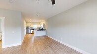 Located at 1933 Argo Rd in Conroe, Texas, this single-floor, 2-bedroom, 2-bathroom home offers a clean, modern aesthetic throughout. The open kitchen is well-appointed with white shaker-style cabinetry, dark granite countertops, and a full suite of stainless steel appliances including a refrigerator, dishwasher, over-the-range microwave, and electric range. Light wood-style flooring runs through the kitchen and living areas, complementing the soft, neutral wall tones that carry consistently throughout the home. A sliding door in the kitchen provides direct access to a private outdoor balcony with views of mature surrounding trees. The living room is open and bright, featuring a ceiling fan with light fixture and a large window that allows natural light to fill the space. Both bedrooms are carpeted and offer ceiling fans, windows with outdoor views, and easy access to a hallway closet. The primary bedroom is notably spacious with vaulted-style ceilings and double-door entry. Both bathrooms are finished with white cabinetry, dark granite countertops, and wood-style flooring. One bathroom features a full tub-shower combo with a textured white surround. A hallway with a dedicated closet connects the living areas to the bedrooms, providing practical storage and a well-organized layout throughout.