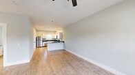 Located at 1933 Argo Rd in Conroe, Texas, this single-floor, 2-bedroom, 2-bathroom home offers a clean, modern aesthetic throughout. The open kitchen is well-appointed with white shaker-style cabinetry, dark granite countertops, and a full suite of stainless steel appliances including a refrigerator, dishwasher, over-the-range microwave, and electric range. Light wood-style flooring runs through the kitchen and living areas, complementing the soft, neutral wall tones that carry consistently throughout the home. A sliding door in the kitchen provides direct access to a private outdoor balcony with views of mature surrounding trees. The living room is open and bright, featuring a ceiling fan with light fixture and a large window that allows natural light to fill the space. Both bedrooms are carpeted and offer ceiling fans, windows with outdoor views, and easy access to a hallway closet. The primary bedroom is notably spacious with vaulted-style ceilings and double-door entry. Both bathrooms are finished with white cabinetry, dark granite countertops, and wood-style flooring. One bathroom features a full tub-shower combo with a textured white surround. A hallway with a dedicated closet connects the living areas to the bedrooms, providing practical storage and a well-organized layout throughout.