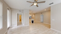 Located at Vineland Resort Way in Orlando, Florida, this well-appointed 2-bedroom, 2-bathroom residence offers a bright and cohesive living environment spread across a single floor. Light wood-look tile flooring flows consistently throughout, creating a clean, unified aesthetic.

The open-plan kitchen is a standout feature, showcasing crisp white cabinetry, a full suite of stainless steel appliances including a refrigerator with ice maker, range, and built-in microwave, as well as a large central island with a white countertop ideal for dining or meal preparation. Globe pendant lights above the island add a modern, decorative touch, while recessed lighting and a tile backsplash complete the contemporary look.

Both bedrooms are comfortably sized, filled with natural light from multiple windows fitted with white blinds, and equipped with ceiling fans. The primary bedroom connects to a walk-in closet with wire shelving, providing ample organized storage. A second walk-in closet is also present elsewhere in the home.

The two bathrooms are finished in a neutral palette with light tile flooring and white vanities. One features a soaking tub with a marble-style surround, while the other offers a glass-enclosed walk-in shower, also with a marble-look tile finish. Three closets in total ensure excellent storage throughout this thoughtfully designed Orlando residence.