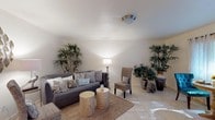 Located at 2711 Allen Rd in Tallahassee, Florida, this single-floor residence offers a well-organized and comfortable layout. The living area sets a relaxed tone with light tile flooring, a neutral color palette, and natural accents including lush potted plants and woven furnishings. A jute area rug anchors the seating arrangement, complemented by rustic wood stool side tables and a classic floor lamp that adds warm ambient lighting.

The dining area is bright and inviting, featuring a large window dressed with sheer patterned curtains that allow natural light to fill the space. A round pedestal table paired with tufted teal accent chairs introduces a vibrant pop of color against the light walls and tile floors.

The kitchen is equipped with wood cabinetry, granite-style countertops, a textured tile backsplash, and a window that brings in additional natural light. The bedrooms are comfortably sized, each with tile flooring and area rugs for added warmth. The primary bedroom includes generous closet space and a large window with sheer white curtains, creating a serene retreat. A full bathroom with warm wood vanity cabinetry, granite countertops, and a shower-tub combination rounds out the home, offering both practicality and comfort throughout.
