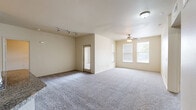 Located at 21 Gramercy Park Dr in Bryan, Texas, this two-story home offers 2 bedrooms and 2 bathrooms across a well-organized layout. The main living level hosts the majority of the living space, while the ground floor provides an attached garage with an automatic opener, offering secure and convenient parking.

The open-concept kitchen and living area serves as the heart of the home. The kitchen is well-appointed with rich dark-brown cabinetry, granite-style countertops, a peninsula with a built-in sink, and a full suite of stainless steel appliances including a range, microwave, and refrigerator. Wood-look flooring and track lighting complete the polished look.

Both bedrooms feature plush carpeting and ceiling fans, with multiple windows allowing for natural light. The primary bedroom is generously sized and includes direct access to a dedicated bathroom and a closet. The second bedroom is comfortable and similarly appointed.

Each of the two bathrooms is finished with dark wood cabinetry, granite-style countertops, wood-look flooring, and a full soaking tub with a tiled surround. A hallway connects the upper-level rooms, with a staircase providing access between floors. Neutral wall tones and clean finishes throughout lend the home a consistent, move-in-ready aesthetic.