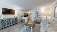 Located at 2130 Mayport Rd in Jacksonville, FL, this well-appointed 1-bedroom, 1-bathroom unit offers a thoughtfully designed coastal aesthetic throughout. The open-concept main living area seamlessly combines the living room, dining space, and kitchen into one cohesive layout, finished with durable wood-look flooring and crown molding. The living room features a bright, airy feel with natural light streaming through large windows, complemented by neutral tones and beach-inspired accents. The kitchen is equipped with stainless steel appliances — including a refrigerator, range, and microwave — white shaker cabinetry, granite countertops, and a peninsula with bar seating, making it both functional and stylish. An in-unit washer is also present. The spacious primary bedroom provides a comfortable retreat, complete with two closets, a natural light-filled window, and ample room for furnishings. The bathroom features white subway tile surrounding a full soaking tub and shower combo, granite countertops, and wood-look flooring, consistent with the home's cohesive design. Two closets offer generous storage throughout the unit. The overall ambiance reflects a relaxed coastal charm, making this an inviting and practical living space.