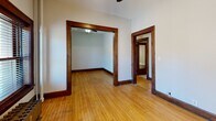 Located at 225 W 15th St in Minneapolis, MN, this one-bedroom, one-bathroom unit offers a compact yet characterful layout spread across a single floor. The space showcases classic architectural details throughout, including warm hardwood floors, rich dark wood door casings, and traditional baseboards that lend a sense of historic charm.

The living room is an open, light-filled area featuring a ceiling fan and hardwood flooring, with wide doorways framed by bold dark wood trim that connect seamlessly to adjacent rooms. Natural light filters in through windows dressed with classic blinds, enhancing the bright, airy feel of the space.

The kitchen retains its vintage character with original wood cabinetry featuring glass-front upper doors, a utility sink, and a distinctive tile floor in a deep, earthy pattern. The cabinetry provides functional storage while contributing to the old-world aesthetic of the room.

A narrow hallway connects the main living areas to the bedroom and bathroom, with hardwood floors continuing underfoot. The hallway provides glimpses into the adjoining rooms, reinforcing the cohesive layout of the unit.

The bathroom is a standout feature, centered around a classic freestanding clawfoot bathtub set atop traditional penny tile flooring — a true nod to early 20th-century design. The bedroom is a cozy, well-defined space with a ceiling fan, hardwood floors, a window with natural light, and a radiator for heating.