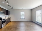 Located at 5202 Centennial Blvd in Nashville, TN, this single-story, one-bedroom, one-bathroom unit offers a thoughtfully designed open-concept layout that seamlessly connects the kitchen and living area. Warm hardwood-style flooring runs throughout the main living spaces, lending a cohesive and inviting feel to the interior.

The kitchen is well-appointed with dark espresso cabinetry extending to the ceiling for generous storage, stainless steel appliances including a refrigerator, electric range, microwave, and dishwasher, complemented by granite-style countertops and a classic herringbone-pattern tile backsplash. Track lighting overhead adds a modern, functional touch. A window in the living area allows natural light to fill the open space.

The bedroom is a comfortable size, featuring hardwood-style flooring and access to a double-door closet, providing ample storage. An additional door connects conveniently to the rest of the unit.

The bathroom is finished in a clean, modern style with large-format white tile flooring, a dark vanity with a white countertop and undermount sink, and a full bathtub and shower combination. The overall ambiance of the unit is contemporary and clean, suited for efficient, modern living in Nashville.