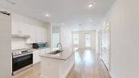 Located at 2652 S Main St NW in Kennesaw, Georgia, this single-floor, three-bedroom, three-bathroom home offers a clean, modern design with a bright and airy aesthetic throughout. The open-concept layout connects the kitchen and living area seamlessly, creating an inviting and functional living space. The kitchen is a standout feature, showcasing white shaker cabinetry, a subway tile backsplash, granite countertops, and a central island with a built-in sink — all complemented by stainless steel appliances including a refrigerator with ice maker, range, and microwave. Light hardwood flooring runs throughout the main living areas, enhancing the home's fresh, contemporary feel. Large windows and a glass door in the living area allow natural light to fill the space while offering views to the exterior. The primary bedroom is a comfortable size and connects to a dedicated closet with built-in wire shelving. Bedrooms feature plush carpeting, adding warmth and comfort. The bathrooms maintain the home's consistent design language, featuring granite-topped vanities with white cabinetry and clean white subway tile walk-in showers. Additional storage is provided through a well-sized closet with wire shelving. The overall palette of crisp whites and light neutrals gives the home a polished, move-in-ready appearance.
