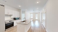 Located at 2652 S Main St NW in Kennesaw, Georgia, this single-floor, three-bedroom, three-bathroom home offers a clean, modern design with a bright and airy aesthetic throughout. The open-concept layout connects the kitchen and living area seamlessly, creating an inviting and functional living space. The kitchen is a standout feature, showcasing white shaker cabinetry, a subway tile backsplash, granite countertops, and a central island with a built-in sink — all complemented by stainless steel appliances including a refrigerator with ice maker, range, and microwave. Light hardwood flooring runs throughout the main living areas, enhancing the home's fresh, contemporary feel. Large windows and a glass door in the living area allow natural light to fill the space while offering views to the exterior. The primary bedroom is a comfortable size and connects to a dedicated closet with built-in wire shelving. Bedrooms feature plush carpeting, adding warmth and comfort. The bathrooms maintain the home's consistent design language, featuring granite-topped vanities with white cabinetry and clean white subway tile walk-in showers. Additional storage is provided through a well-sized closet with wire shelving. The overall palette of crisp whites and light neutrals gives the home a polished, move-in-ready appearance.