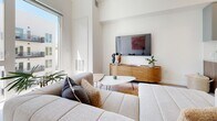 Located at 730 16th Street in Sacramento, this one-bedroom, one-bathroom residence at The Mansion offers a thoughtfully designed single-floor layout with modern finishes and a clean, contemporary aesthetic throughout.

The open-concept living and dining area is anchored by large floor-to-ceiling windows that draw in generous natural light and provide views of the surrounding building exterior. The living space features light wood-style flooring, elevated ceiling heights, and a bright, neutral color palette that enhances the sense of openness.

The kitchen is well-appointed with two-tone cabinetry—combining matte gray upper cabinets with warm wood lower cabinets—white tile backsplash, stainless steel appliances including a full-size refrigerator, range, microwave, and dishwasher, and ample counter space. A dining area adjacent to the kitchen comfortably accommodates a full table and chairs.

The bedroom features soft carpet flooring, a large window with exterior views, and access to a dedicated walk-in closet with built-in shelving. The bathroom includes wood-toned cabinetry, a wide vanity mirror, wood-style flooring, and a full soaking tub with marble-style tile surround. An in-unit stacked washer and dryer with additional built-in shelving completes the space.