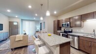 Located at 4140 Silo View Dr in DeForest, Wisconsin, this well-appointed single-floor residence offers a thoughtfully designed layout with modern finishes throughout. The open-concept kitchen is a standout feature, boasting rich dark-toned cabinetry, granite countertops, a large center island with bar seating illuminated by pendant lighting, and a full suite of stainless steel appliances including a refrigerator, range, microwave, and dishwasher. Wood-look flooring flows through the kitchen and living areas, adding warmth and cohesion to the space. The living area is bright and inviting, with access to natural light through sliding glass doors fitted with vertical blinds. Bedrooms are carpeted for comfort and offer a calm, neutral aesthetic. The residence includes two full bathrooms, each finished with granite vanity countertops, dark wood cabinetry, large mirrors, and tub-shower combinations. A dedicated laundry area houses a stacked washer and dryer unit, adding everyday convenience. An additional flexible room with carpet provides space for a home office or sitting area. Recessed lighting throughout enhances the clean, contemporary ambiance of this well-designed residence.