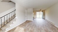 Located at 603 E Northfield Blvd in Murfreesboro, TN, this two-story residence offers a well-organized layout spread evenly across two floors. The main level features an open living room bathed in natural light from a large sliding glass door, highlighted by light wood-look flooring, neutral walls, a ceiling fan, and a baseboard heating system. A stylish staircase with black metal balusters connects the two levels. The kitchen is equipped with white shaker-style cabinetry, granite-look countertops, stainless steel appliances including a refrigerator, range, and dishwasher, and a flush-mount ceiling light. Upstairs, two carpeted bedrooms each include ceiling fans for comfort. The primary bedroom features a walk-in closet and a wall-mounted AC unit, while the second bedroom offers a double-door closet. Both bedrooms share a clean, bright full bathroom with a white vanity, granite-look countertop, and a tiled tub-shower combination. Wood-look tile flooring carries through the bathroom, complementing the cohesive design throughout. The neutral color palette and updated finishes create a clean, move-in-ready atmosphere throughout the home.