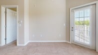 Located at 4000 Walden Way in Flowery Branch, Georgia, this one-bedroom, one-bathroom residence offers a thoughtfully designed single-floor layout. The open-concept kitchen and living area serves as the heart of the home, featuring warm hardwood-style flooring in the kitchen, a breakfast bar with granite-style countertops, honey-toned cabinetry, and black appliances including a range, microwave, and refrigerator. The living area transitions seamlessly to soft carpeting and is bathed in natural light through large windows, with access to an outdoor balcony. A ceiling fan adds comfort to the space. The carpeted hallway connects the main living area to the private quarters, where the spacious bedroom offers a ceiling fan, a large window overlooking outdoor greenery, and plush carpet flooring. The walk-in closet provides generous storage with wire shelving systems along multiple walls. The bathroom is clean and functional, featuring a soaking tub with a tiled surround, built-in shelving, and a full shower curtain setup. Neutral warm beige tones throughout create a cohesive and inviting ambiance across the entire residence.