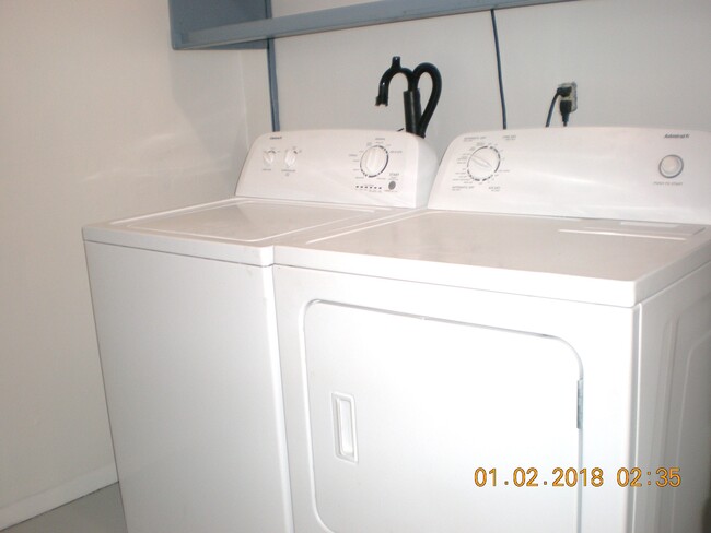 Washer and dryer in lower level laundry room with shelves for storage and room for folding table - 1160 Clinton St
