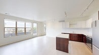 This three-bedroom, two-bathroom residence in Bismarck, North Dakota offers a thoughtfully designed single-floor layout with a clean, modern aesthetic throughout. The open-concept living, dining, and kitchen area forms the heart of the home, filled with natural light streaming through large windows and a glass balcony door that opens to an outdoor balcony with sweeping city views. Light-toned luxury vinyl flooring and crisp white walls create a bright, airy atmosphere, complemented by track lighting overhead.

The kitchen is a standout feature, equipped with rich dark-wood cabinetry contrasted by white upper cabinets, light quartz countertops, a tile backsplash, stainless steel appliances, and a generous center island—ideal for both cooking and casual dining. A pantry provides additional storage.

Three well-proportioned bedrooms each feature track lighting and light flooring. The primary bedroom includes a built-in floor-to-ceiling wardrobe with sleek white cabinetry. Additional bedrooms benefit from windows offering city views. The two bathrooms are finished in a clean, neutral palette—one with a walk-in shower and the other with a full bathtub. Two closets provide ample storage throughout the unit.