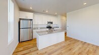 Located at 5875 Balsam Dr in Hudsonville, Michigan, this single-story, one-bedroom, one-bathroom unit offers a clean, modern design with a bright and cohesive aesthetic throughout. Light hardwood flooring flows seamlessly across every room, complementing the crisp white walls and recessed lighting that keep the space feeling open and airy.

The open-concept kitchen, dining, and living area serves as the heart of the unit. The kitchen is well-appointed with white shaker-style cabinetry reaching toward the ceiling, granite countertops, a center island with an undermount sink, and a full suite of stainless steel appliances including a gas range, microwave, dishwasher, and refrigerator. Natural light enters through windows that offer views of the surrounding neighborhood.

The bedroom is comfortably sized, featuring a window with neighborhood views, a built-in closet with hanging storage, and direct access to the in-unit laundry area — a convenient and practical feature. The hallway connects all areas of the unit efficiently, with additional closet storage available.

The bathroom is finished with white cabinetry, a granite-topped vanity with an undermount sink, brushed nickel hardware, and a full tub-shower combination. Throughout the unit, the design is consistent and contemporary, making for a polished, move-in-ready living space.
