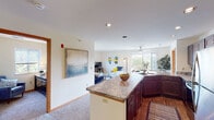 This single-floor residence offers a thoughtfully designed open-concept layout that seamlessly connects the kitchen, dining, and living areas. The kitchen is a standout feature, equipped with rich dark wood cabinetry, stainless steel appliances including a refrigerator, range, and microwave, and a generous granite-topped island that serves as both a workspace and a natural divider between the kitchen and living spaces. Recessed lighting illuminates the area, adding a polished finish.

The living room is bright and welcoming, featuring large windows that flood the space with natural light and a sliding glass door that opens onto a private balcony, offering pleasant outdoor views. A ceiling fan overhead adds both style and functionality to the dining area adjacent to the balcony.

The residence includes multiple carpeted bedrooms, each featuring windows with outdoor views, providing a calm and comfortable retreat. The bedrooms are well-proportioned with ample wall space. Two bathrooms serve the unit, each featuring dark wood vanities with undermount sinks, well-lit mirrors, and clean, neutral finishes. One bathroom includes wood-look flooring, while both maintain a consistent, refined aesthetic throughout the home.