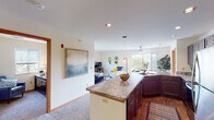 This single-floor residence offers a thoughtfully designed open-concept layout that seamlessly connects the kitchen, dining, and living areas. The kitchen is a standout feature, equipped with rich dark wood cabinetry, stainless steel appliances including a refrigerator, range, and microwave, and a generous granite-topped island that serves as both a workspace and a natural divider between the kitchen and living spaces. Recessed lighting illuminates the area, adding a polished finish.

The living room is bright and welcoming, featuring large windows that flood the space with natural light and a sliding glass door that opens onto a private balcony, offering pleasant outdoor views. A ceiling fan overhead adds both style and functionality to the dining area adjacent to the balcony.

The residence includes multiple carpeted bedrooms, each featuring windows with outdoor views, providing a calm and comfortable retreat. The bedrooms are well-proportioned with ample wall space. Two bathrooms serve the unit, each featuring dark wood vanities with undermount sinks, well-lit mirrors, and clean, neutral finishes. One bathroom includes wood-look flooring, while both maintain a consistent, refined aesthetic throughout the home.