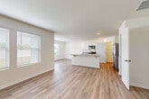 This well-appointed two-story home in Rossville, GA offers a clean, modern aesthetic with light wood-look flooring and neutral tones carried consistently throughout both levels. The main floor features an open-concept layout where the living area flows seamlessly into a well-equipped kitchen. The kitchen is outfitted with white shaker-style cabinetry, granite countertops, a central island with a sink, and stainless steel appliances including a range, microwave, dishwasher, and French door refrigerator. A dedicated dining area adjacent to the kitchen is brightened by large windows with exterior views. Upstairs, the staircase with a white banister leads to multiple spacious bedrooms, each featuring wood-look flooring and ceiling fans with light fixtures. The primary bedroom includes access to an en suite bathroom with a dual-sink vanity topped with granite countertops, white cabinetry, and a walk-in closet. A dedicated laundry room houses a full-size washer and dryer. Throughout the home, abundant natural light streams in through numerous windows fitted with blinds, contributing to an airy and welcoming atmosphere across both floors.