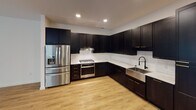 This two-story residence on Bulfinch Road in Charlotte's 28209 zip code showcases a cohesive contemporary design defined by a striking contrast between dark cabinetry and bright, white walls. Light hardwood flooring flows consistently throughout both levels, lending warmth and visual continuity to the space.

The open-concept main living area is generously proportioned, with large windows that invite abundant natural light and ceiling fans overhead. The kitchen is a standout feature, equipped with tall dark shaker-style cabinetry accented by gold hardware, marble-look countertops, a white subway tile backsplash, a farmhouse sink, and a full suite of stainless steel appliances including a gas range and French door refrigerator.

Bedrooms are bright and well-sized, each benefiting from natural light through large windows and ceiling fans. Bold black interior doors serve as an architectural accent throughout the home.

The bathrooms mirror the kitchen's design sensibility, featuring dark vanities with gold hardware, marble-look countertops, and matte black fixtures. A full bath includes a soaking tub with tiled surround, while a half bath provides a refined vanity with an undermount sink. A staircase connects the two floors, completing this well-appointed and design-forward home.