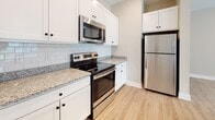 Located at 17151 Windward Blvd in Milford, Delaware, this single-floor residence offers a thoughtfully designed open-concept layout that seamlessly connects the kitchen, dining, and living areas. Light wood-look flooring flows throughout the main living spaces, contributing to a bright and airy atmosphere. The living room is generously proportioned, featuring recessed lighting, neutral warm-toned walls, and a sliding glass door that invites natural light and provides views of the surrounding greenery.

The kitchen is well-appointed with crisp white shaker-style cabinetry, granite countertops, a classic white subway tile backsplash, and a full suite of stainless steel appliances including a range, over-the-range microwave, and refrigerator. A peninsula with pendant lighting adds both functionality and visual interest, creating a natural divide between the kitchen and living areas.

The bedrooms are carpeted for comfort, with one featuring dual windows and a ceiling fan, creating a serene retreat. An additional bedroom includes access to a walk-in closet. The bathroom is clean and functional, complete with white cabinetry, a soaking tub, and wood-look flooring. Throughout, the space maintains a cohesive, modern aesthetic with neutral tones and quality finishes.