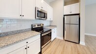 Located at 17151 Windward Blvd in Milford, Delaware, this single-floor residence offers a thoughtfully designed open-concept layout that seamlessly connects the kitchen, dining, and living areas. Light wood-look flooring flows throughout the main living spaces, contributing to a bright and airy atmosphere. The living room is generously proportioned, featuring recessed lighting, neutral warm-toned walls, and a sliding glass door that invites natural light and provides views of the surrounding greenery.

The kitchen is well-appointed with crisp white shaker-style cabinetry, granite countertops, a classic white subway tile backsplash, and a full suite of stainless steel appliances including a range, over-the-range microwave, and refrigerator. A peninsula with pendant lighting adds both functionality and visual interest, creating a natural divide between the kitchen and living areas.

The bedrooms are carpeted for comfort, with one featuring dual windows and a ceiling fan, creating a serene retreat. An additional bedroom includes access to a walk-in closet. The bathroom is clean and functional, complete with white cabinetry, a soaking tub, and wood-look flooring. Throughout, the space maintains a cohesive, modern aesthetic with neutral tones and quality finishes.