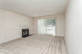 This single-story space in Atlanta, GA offers a well-organized layout designed for comfortable everyday living. The living room serves as the central gathering area, highlighted by a classic fireplace with a white mantel and sliding glass doors that open to a balcony, allowing natural light to pour in and providing views of the surrounding area. Neutral-toned carpet covers the floor, complementing the warm, understated color palette throughout.

Adjacent to the living room, a dedicated dining area features a chandelier overhead and a pass-through window connecting to the kitchen, creating an open and communicative feel between the spaces. The galley-style kitchen is fitted with white cabinetry, light countertops, a gas range, a dishwasher, a refrigerator, and a double sink. Dark hardwood-style flooring grounds the kitchen and flows toward a laundry area with louvered closet doors.

The space includes two bedrooms, each carpeted and equipped with ceiling fans and windows that bring in natural light. Both bathrooms are functional and straightforward, each featuring a tiled tub-shower combination, a vanity with storage, and tile flooring. Textured ceilings are consistent throughout, contributing to the cohesive character of this Atlanta residence.