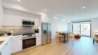 Unit 409 at 1112 Locust Street in Long Beach, California, is a thoughtfully designed one-bedroom, one-bathroom residence offering a clean, modern aesthetic throughout. The open-concept layout connects the living room and kitchen, creating a cohesive and functional living space bathed in natural light.

The kitchen is a standout feature, showcasing floor-to-ceiling white cabinetry, a neutral tile backsplash, white quartz countertops, and a full suite of stainless steel appliances, including a gas range, built-in microwave, dishwasher, and French door refrigerator. Light wood-tone flooring runs seamlessly throughout, adding warmth to the bright, white interior.

The living room is generously proportioned, anchored by a large sliding glass door that frames city views and allows abundant natural light to fill the space. Recessed lighting throughout the unit adds a clean, polished finish.

The bedroom offers a quiet retreat with a large window overlooking neighborhood rooftops and palm trees, continuing the light wood flooring and crisp white walls. In-unit washer and dryer hookups are conveniently located nearby.

The bathroom features terrazzo tile flooring, a sleek white vanity with black-framed mirror, and a clean, minimalist design. This unit combines contemporary finishes with efficient use of space in the heart of Long Beach.