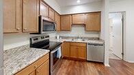 Located at 4315 Wimbleton Ct in South Bend, Indiana, this one-bedroom, two-bathroom single-story home offers a thoughtfully arranged layout that maximizes every square foot of its comfortable footprint. The kitchen is well-appointed with warm honey-toned cabinetry, granite-style countertops, and a full suite of stainless steel appliances including a refrigerator, electric range, over-the-range microwave, and dishwasher. Rich hardwood-style flooring runs through the kitchen and connects seamlessly to the adjacent living room via an open pass-through window, enhancing the sense of connectivity between spaces. The living room features plush carpeting, a ceiling fan, and a large sliding glass door fitted with vertical blinds that invites natural light and outdoor views. The bedroom is generously sized with multiple windows offering ample natural light, soft carpet underfoot, and access to a dedicated closet with louvered bifold doors. Two bathrooms serve the home, one featuring a wide vanity with warm wood cabinetry, a large mirror with overhead lighting, and tile flooring. Additional highlights include two closets for storage, a dedicated laundry area, and a connecting hallway that ties the layout together efficiently.