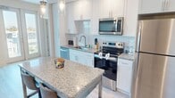 This contemporary 890 square foot apartment offers a well-designed living space with two bedrooms and two bathrooms. The open-concept layout seamlessly integrates the kitchen and living room, creating a spacious feel. The primary bedroom, measuring 140 square feet, provides a comfortable retreat.

The interior boasts modern finishes throughout, including light wood-look flooring and neutral wall colors. Large windows in the living area and bedrooms allow ample natural light and offer city views. The living room features a stylish mix of furniture, including a gray sectional sofa and a vibrant yellow accent chair.

The kitchen is equipped with stainless steel appliances, white cabinetry, and a granite countertop island that doubles as a dining area. Both bathrooms are well-appointed with granite countertops and modern fixtures. The apartment includes two closets for storage, complemented by wire shelving systems.

A standout feature is the balcony, accessible through a glass door, providing outdoor space and panoramic views of the surrounding area. Ceiling fans in the bedrooms and living area ensure comfort and air circulation.

Located at 201 Day B2.1, this single-story apartment combines functionality with modern aesthetics, offering a comfortable and stylish urban living experience.