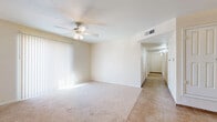 This single-floor residence offers a clean, neutral palette throughout, creating a bright and welcoming atmosphere. The living area is generously sized, featuring plush wall-to-wall carpeting, a ceiling fan with integrated lighting, and large sliding glass doors dressed with vertical blinds that invite an abundance of natural light. A hallway connects the living space to the private areas of the home, finished with tile flooring that extends through the main circulation areas.

The kitchen is well-appointed with warm honey-toned wood cabinetry, a full suite of white appliances including a range, microwave, and refrigerator, and tile flooring. A pantry closet provides additional storage directly off the kitchen.

The bedrooms are carpeted and offer a calm, comfortable retreat. Each room features windows with blinds, allowing for natural light and outside views. One bedroom includes a closet with paneled doors, offering practical storage.

The bathroom is finished with large-format stone-look tile on both the floor and the full tub surround, complemented by warm wood cabinetry above. The overall design of the space is straightforward and functional, with a consistent neutral color scheme that provides a versatile backdrop throughout.