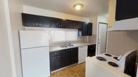 This two-floor space offers a practical and straightforward layout designed for everyday living. The kitchen is a standout area, featuring bold dark cabinetry that contrasts with light countertops, a double-basin sink positioned beneath a window with natural light, and white appliances including a refrigerator, dishwasher, and electric range. Tile flooring and a textured ceiling complete the kitchen's functional aesthetic.

The bedrooms are carpeted and finished with neutral-toned walls, each equipped with ceiling fans for added comfort. One bedroom benefits from a large sliding door with vertical blinds, allowing generous natural light to fill the space, while another features a standard window with blinds. Built-in closets are present in the bedrooms, providing practical storage solutions.

The bathrooms include tile flooring throughout. One bathroom offers a soaking tub with a shower curtain rod and towel bars, while a second half-bath features a granite-topped vanity, a framed mirror, and updated lighting fixtures. Together, the two levels create a well-organized living environment with consistent, neutral finishes throughout.
