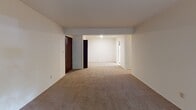 Located at 1 Court Blvd in Michigan City, Indiana, this single-floor residence offers a practical and well-organized layout. The living area is generously sized, featuring neutral-toned carpet throughout and clean white walls that create a bright, open atmosphere. A built-in closet with wire shelving near the main living space provides convenient storage. Windows in the living and bedroom areas allow natural light to filter in, offering views of the surrounding greenery.

The kitchen is equipped with warm, medium-toned wood cabinetry both above and below the counters, complemented by light laminate countertops, a double stainless steel sink, and a built-in dishwasher, providing a functional and efficient cooking space.

The bedrooms are carpeted and spacious, each featuring ample closet space with built-in shelving and rods for organized storage. Natural light enters through windows overlooking outdoor greenery, lending a calm and comfortable feel to each room.

Two bathrooms serve the residence. One features a full tub-shower combination, a rich wood vanity with a granite-style countertop, tile flooring, and a large mirror. The second bathroom includes a standalone walk-in shower with chrome fixtures. Both bathrooms maintain a clean, neutral aesthetic throughout.