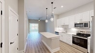 Located at 901 St Albans Dr in Raleigh, NC, this well-appointed two-bedroom, one-bathroom home offers a thoughtfully designed single-floor layout with modern finishes throughout. The open-concept kitchen and living area serves as the heart of the home, featuring a large center island with crisp white countertops, white shaker-style cabinetry, a classic subway tile backsplash, and a full suite of stainless steel appliances including a refrigerator, range, microwave, and dishwasher. Stylish pendant lighting and recessed ceiling lights add warmth and depth to the space. Light wood-tone vinyl plank flooring flows throughout the main living areas, complementing the neutral, airy color palette. Large windows in the living area flood the space with natural light and offer views of the surrounding greenery. The primary bedroom is generously sized and includes a well-organized closet with built-in shelving and dual hanging rods. The second bedroom features plush carpeting and a ceiling fan. The shared bathroom is elegantly appointed with a dual-sink vanity, gold fixtures, framed mirrors, and a soaking tub with a marble-tile surround. A smart thermostat adds a modern touch of convenience to this clean and contemporary home.