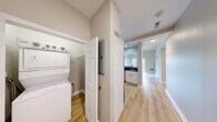 Located at 307 Central St in Hudson, Massachusetts, this single-floor residence offers a well-designed layout with a clean, modern aesthetic throughout. The living area is highlighted by soaring vaulted ceilings that create an open, airy atmosphere, complemented by light hardwood-style flooring and neutral wall tones that run consistently through the space. Large sliding glass doors lead to a private balcony overlooking lush greenery, filling the room with natural light.

The kitchen is equipped with white shaker-style cabinetry, dark countertops, and a full suite of stainless steel appliances including a refrigerator, range, and microwave. A pass-through window connects the kitchen to the living area, enhancing the open feel of the floor plan.

The bedroom features vaulted ceilings, a generously sized closet, and direct access to a full bathroom finished with tile flooring and a shower-tub combination. A dedicated in-unit laundry closet accommodates a stacked Whirlpool washer and dryer, adding everyday convenience. Recessed lighting and ample windows ensure the space remains bright throughout. The overall design is move-in ready, offering a comfortable and functional living environment in a desirable Hudson location.