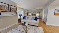 This single-floor residence offers a thoughtfully designed layout that combines comfort and modern style throughout its key living spaces. The living area serves as the heart of the home, featuring warm hardwood flooring, neutral gray walls, and large windows with slatted blinds that allow natural light to filter in. A cream sofa accented with navy blue throw pillows anchors the space, complemented by a gold geometric side table and a soft area rug, creating an inviting atmosphere for relaxing or entertaining.

The bedroom continues the home's cohesive aesthetic with the same rich hardwood floors. A full-size bed dressed in navy and white bedding is framed by matching black open-shelf nightstands and elegant metallic wall art. French doors with plantation shutters offer the potential for natural light and outdoor access. The bedroom also features a substantial wooden dresser, adding generous storage.

The kitchen is well-equipped with stainless steel appliances, including a full-size refrigerator, dishwasher, microwave, and range. Light wood cabinetry with frosted glass upper doors, granite countertops, and a classic white subway tile backsplash give the kitchen a clean, functional character. Tile flooring ties the space together neatly.

The bathroom mirrors the kitchen's refined touches, showcasing granite countertops, a white vanity, a large framed mirror with accent lighting, and tile flooring, completing this well-rounded residence.