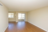 This single-floor residence offers a well-organized layout designed for comfortable everyday living. The living area serves as the heart of the home, featuring warm hardwood-style flooring and a sliding glass door that opens to a private balcony, allowing natural light to fill the space and providing outdoor views of the surrounding neighborhood. Adjacent to the living area, a dining space with a ceiling fan and a wide window adds further brightness and airflow to the common areas.

The galley-style kitchen is efficiently designed with white cabinetry, granite-look countertops, and a full suite of appliances including a refrigerator, electric range with overhead microwave, and dishwasher. Light wood-style flooring and a ceiling light fixture keep the kitchen bright and practical.

The bedrooms are finished with plush carpeting and neutral-toned walls, creating a calm and restful atmosphere. Each room benefits from natural light through well-placed windows. One bedroom features direct access to a bathroom, functioning as a private en-suite arrangement.

The bathroom is appointed with a wide vanity topped with a speckled countertop, a white under-mount sink, white cabinetry, a large mirror with overhead lighting, and a tub-shower combination. Chrome fixtures and a towel bar add clean, functional details throughout. The overall aesthetic is understated and move-in ready.