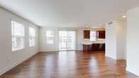 Located at 10858 Telegraph Rd in Ventura, California, this single-floor unit offers a thoughtfully designed open-concept layout that seamlessly connects the living, dining, and kitchen areas. Rich hardwood-style flooring flows throughout the main living spaces, complemented by an abundance of natural light streaming through multiple windows fitted with blinds. A sliding glass door with vertical blinds leads to a private balcony, extending the living space outdoors.

The kitchen is a standout feature, boasting rich dark cabinetry, a mosaic tile backsplash, light quartz countertops, and a curved breakfast bar peninsula. Stainless steel appliances — including a range, microwave, and dishwasher — complete the space, making it both functional and visually appealing.

The bedrooms offer plush neutral carpeting and generous windows that invite natural light, creating comfortable and versatile spaces. A well-appointed bathroom includes a dark wood vanity, white countertop, and hardwood-style flooring, maintaining the cohesive design aesthetic found throughout the unit.

Additional rooms feature clean white walls, recessed lighting, and hardwood-style flooring, providing flexible spaces suited to a variety of needs. The overall ambiance is bright, clean, and modern, reflecting contemporary residential design in the heart of Ventura.