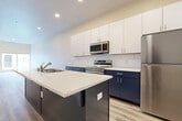 This single-floor unit in Sparks, Nevada offers a well-designed layout with modern finishes and a clean, contemporary aesthetic. The kitchen serves as a central highlight, featuring a striking two-tone cabinet design with navy lower cabinets and crisp white uppers, complemented by light quartz countertops and a classic subway tile backsplash. A central island with an integrated sink adds both workspace and functionality. Stainless steel appliances, including a refrigerator, range, microwave, and dishwasher, complete the kitchen's polished look. Light wood-style flooring runs throughout the main living areas, reflecting natural light and contributing to a bright, open atmosphere. The living space is generously proportioned, with large sliding glass doors that invite natural light and provide outdoor views. The bedroom is carpeted for comfort, features a sizeable window for natural light, and includes a double sliding-door closet offering ample storage. Warm neutral wall tones are consistent throughout, lending a cohesive and inviting ambiance to the entire unit.