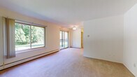 This one-bedroom, one-bathroom unit in Westland, Michigan offers a well-organized single-floor layout designed for comfortable everyday living. The spacious living area is carpeted and filled with natural light, courtesy of a large picture window and sliding glass doors that open onto a private balcony overlooking lush, mature trees. A ceiling fan provides added comfort, while baseboard heating runs along the perimeter walls. Built-in shelving is conveniently accessible from the living space, adding practical storage. A secondary windowed area near the entry provides additional brightness and includes a wall-mounted air conditioning unit.

The galley-style kitchen is efficiently laid out with ample white cabinetry on both sides, offering generous storage and counter space. It is equipped with a white refrigerator, electric range, and dishwasher, all set above warm hardwood-style flooring.

The full bathroom features classic white tile in the tub/shower surround and on the floor, a single-sink vanity with a large mirror, and a clean, bright aesthetic. The overall unit presents a neutral, light color palette throughout, offering a versatile canvas for personalization.