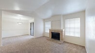 This one-bedroom, one-bathroom unit is thoughtfully laid out across a single floor, making efficient use of its space throughout. The living room serves as the focal point of the home, distinguished by vaulted ceilings that lend an open, airy feel. A classic brick fireplace with a raised hearth anchors the room, flanked by multiple windows fitted with blinds that allow for adjustable natural light. Plush wall-to-wall carpeting runs throughout the living areas and bedroom, contributing to a warm and comfortable atmosphere.

The kitchen is well-equipped with warm wood cabinetry, granite-style countertops, tile flooring, and black appliances including an electric range and over-the-range microwave. A pass-through opening connects the kitchen to the adjoining dining area, which is carpeted and illuminated by a ceiling fixture. The bedroom is a comfortable size with a dedicated window for natural light and neutral walls. The full bathroom features a wide vanity with granite-style countertops, rich wood cabinetry, a large mirror, and tile flooring. A dedicated laundry room includes washer and dryer hookups with built-in wire shelving for added storage.