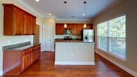 Located at 5400 Garden Lake Dr in Greensboro, NC, this two-story home offers a thoughtfully designed layout with consistent finishes across both levels. Rich hardwood flooring flows throughout the main living areas, complemented by crown molding and neutral warm-toned walls that create a welcoming atmosphere.

The kitchen is a standout feature, showcasing rich cherry wood cabinetry with raised-panel detailing, dark granite countertops, and a full suite of stainless steel appliances including a range, built-in microwave, and refrigerator. A central island with pendant lighting provides additional prep space and opens to the adjacent living area. Recessed lighting and a large window allow natural light to fill the space.

The main living area is generously proportioned, featuring hardwood floors, crown molding, a ceiling fan, and multiple windows that offer views of the surrounding greenery. A half bathroom on the main level includes hardwood flooring, a cherry vanity, and granite countertop.

Upstairs, bedrooms are finished with plush carpeting, ceiling fans, and windows with blinds. A full bathroom features tile flooring, a soaking tub, a cherry vanity with granite countertop, and direct access to an adjoining bedroom. A spacious walk-in closet with wire shelving provides ample storage.