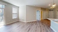Located at 950 Jordan Creek Parkway in West Des Moines, Iowa, this well-appointed 1-bedroom, 2-bathroom unit offers a thoughtfully designed single-floor layout. The kitchen stands out as a centerpiece of the home, showcasing soft gray shaker-style cabinetry that extends to the ceiling, a white quartz island with an undermount sink, stainless steel appliances, a subway tile backsplash, and a built-in wine rack alongside a convenient desk nook. Light wood-look flooring flows throughout the main living and kitchen areas, adding warmth and continuity. The spacious bedroom features plush carpeting, natural light through double windows, and a ceiling fan for added comfort. The primary bathroom is elegantly finished with a dual-sink vanity, shaker-style cabinetry with matte black hardware, large-format tile flooring, and a tiled soaking tub and shower combination — with a dedicated walk-in closet adjacent. A second bathroom provides additional convenience. The living area benefits from natural light and connects seamlessly to a private balcony, offering views of the modern multi-story building exterior. Neutral, soft-tone walls throughout create a clean, contemporary ambiance suited for a variety of styles.