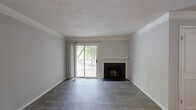 Located at 3100 Sweetwater Road in Lawrenceville, GA, this one-bedroom, two-bathroom residence offers a well-organized single-floor layout designed for comfortable living. Wood-style flooring flows consistently throughout the space, complemented by crown molding and neutral gray tones that give the interior a clean, cohesive aesthetic.

The living room serves as the centerpiece of the home, featuring a wood-burning fireplace with a classic white mantel and a sliding glass door that opens to a private balcony, allowing natural light to fill the space. Adjacent to the living area, the kitchen is thoughtfully designed with white cabinetry, stainless steel appliances, a marble-look countertop that doubles as a breakfast bar, and an under-cabinet range hood — all opening toward the main living and dining areas for an easy, connected feel.

The bedroom is a comfortable, well-lit room with a large window that frames outdoor greenery. Both bathrooms are finished with light flooring and clean white tiled tub-shower combinations. A dedicated laundry closet with side-by-side washer and dryer hookups adds everyday convenience. Textured ceilings and decorative columns further accent the architectural character of this efficiently laid-out home.
