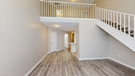 This two-story residence in Horn Lake, Mississippi offers a well-designed layout across two levels, finished with light wood-style flooring and neutral warm-toned walls throughout. The main level makes an immediate impression with soaring ceilings and an open entryway flanked by arched windows that allow generous natural light to fill the space. A white-railed staircase with carpeted treads rises to an upper-level landing overlooking the living area below, adding architectural depth and visual openness.

The kitchen is equipped with white cabinetry, light stone-toned countertops, and a full suite of stainless steel appliances, including a range, microwave, and refrigerator. A peninsula counter provides additional workspace and casual dining potential, flowing naturally into the main living area.

Both bedrooms are located on the upper level, each featuring ceiling fans and ample closet space. The primary bedroom includes direct access to a private bathroom, while the second full bathroom serves the additional bedroom. Both bathrooms are finished with white vanities and light countertops, maintaining the home's clean, consistent aesthetic. The second bathroom features a tub-shower combination with sliding glass doors.