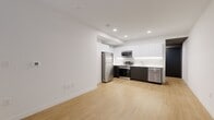 Located at 1001 N Orange St in Wilmington, Delaware, this modern 2-bedroom, 1-bathroom unit offers a clean, contemporary design with a consistent aesthetic throughout. Light wood-tone flooring runs throughout the entire space, complementing the bright white walls and recessed lighting that give the unit an open, airy feel.

The combined kitchen and living area serves as the heart of the unit. The kitchen is outfitted with sleek two-tone cabinetry—white upper cabinets with dark lower cabinets—paired with white countertops, under-cabinet lighting, and a full suite of stainless steel appliances including a refrigerator, range, microwave, and dishwasher.

Both bedrooms are bright and cleanly finished, with large windows that allow natural light to fill the rooms. The primary bedroom offers a comfortable footprint with a dedicated closet featuring built-in shelving and hanging rods. The second bedroom also includes a window and closet access.

The bathroom features a tub-shower combination with large-format white wall tiles, a herringbone-patterned tile floor, a dark wood vanity with a white countertop, and a lighted mirror. A dedicated in-unit laundry room houses a side-by-side Bosch washer and dryer with overhead shelving, adding everyday convenience to this well-appointed space.