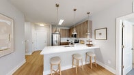 Located at 1880 Maple Dr NW in Kennesaw, GA, this single-floor residence offers two bedrooms and two bathrooms with a thoughtfully designed, open layout. The kitchen is a standout feature, showcasing wood-toned cabinetry extending to the ceiling, a white subway tile backsplash, stainless steel appliances, and a generous quartz-topped peninsula with seating — ideal for casual dining and entertaining. Light wood-style flooring runs throughout the main living areas, enhancing the home's bright and airy feel.

The living room receives abundant natural light through large windows with plantation-style blinds, complemented by a ceiling fan overhead. A glass-paned door adds to the sense of openness. Both bedrooms are carpeted and well-sized, with the primary bedroom featuring a ceiling fan and the secondary bedroom offering a large window with outdoor views. Each bedroom includes a dedicated closet, with the primary featuring a walk-in closet equipped with built-in shelving and hanging rods.

The primary bathroom impresses with a dual-sink vanity, wood-grain cabinetry, white quartz countertops, and bright vanity lighting. The second bathroom offers a tub-shower combination with full subway tile surround and a single-sink vanity. Together, these spaces create a cohesive, modern living environment with clean finishes throughout.