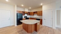 Located in Building D of a residential community in Frederick, Maryland, Unit 408 at 5234 Black Locust Pike presents a thoughtfully laid-out single-floor residence with a clean, neutral aesthetic throughout. The open kitchen serves as a functional centerpiece, featuring rich warm-toned wood cabinetry, granite countertops, a center island with additional prep space, and black appliances including a refrigerator, electric range, and dishwasher. Recessed lighting illuminates the kitchen, adding a polished finish to the space. The main living area is finished with durable hardwood-style flooring and benefits from natural light streaming in through large windows fitted with blinds, creating a bright and welcoming atmosphere. Bedrooms are carpeted for comfort, with ample wall space and windows that invite in natural light. The unit includes two bathrooms — a full bath with a tub/shower combination, warm wood vanity, white countertop, and wood-look tile flooring, as well as a second bath similarly appointed with a wood vanity and crisp white surfaces. Grab bars in the full bath add an element of accessibility. Throughout the unit, clean white walls, white trim, and consistent flooring choices create a cohesive and move-in-ready environment.