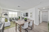 This thoughtfully designed 1-bedroom, 1-bathroom residence offers a bright, open-concept layout that seamlessly connects the kitchen, dining, and living areas. Light wood-tone flooring flows throughout the main living spaces, creating a cohesive and airy atmosphere. The modern kitchen is a standout feature, showcasing crisp white shaker cabinetry, a tiled backsplash, quartz countertops, a center island with an undermount sink, and a full suite of stainless steel appliances including a gas range, microwave, and refrigerator. Pendant lighting above the island adds a polished touch. The living room is generously proportioned, filled with natural light from large windows, and offers direct access to a private balcony. A dedicated dining area completes the open living space. The bedroom is a comfortable retreat, featuring plush carpet, a wide window with ample natural light, and access to a dedicated closet. The full bathroom is clean and functional, featuring a white vanity with ample storage, a full soaking tub with tiled surround, and wood-tone flooring. A hallway connects the private spaces efficiently. The entry foyer provides a welcoming transition into the home, finished with the same warm wood-tone flooring found throughout.